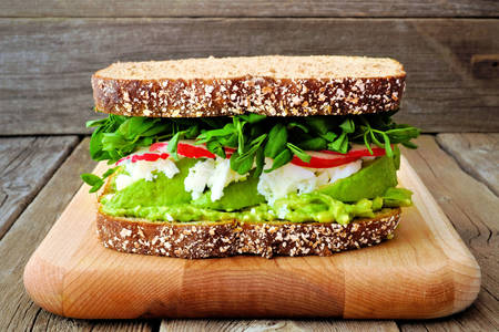 Sandwich mit Gemüse und Käse auf einem Brett