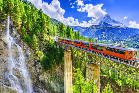 Panorámás vonat a hegyekben, egy vízeséssel