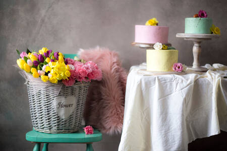Korpa sa cvećem i kolači na stolu