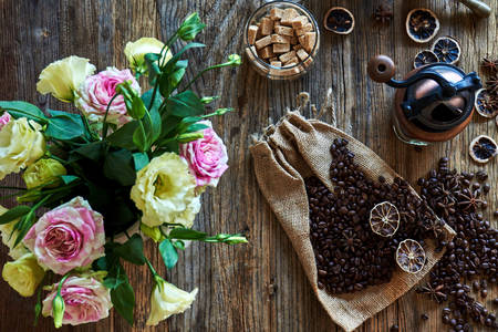 Granos de café sobre una mesa con flores