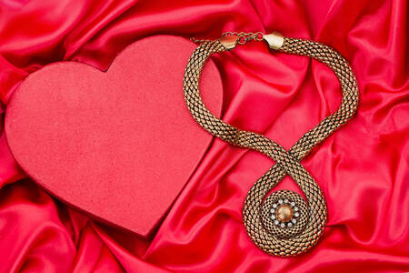 Heart and necklace on red satin