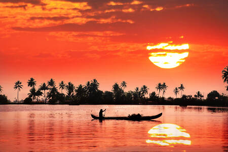 Pêcheur dans un bateau au coucher du soleil