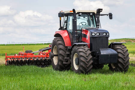 Rode tractor met hooibalenpers