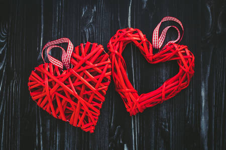 Червоні плетені серця на темному дерев'яному тлі