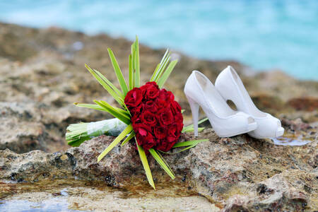 Sapatos de casamento e buquê à beira-mar