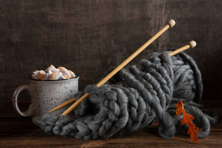 A cup with marshmallows and knitting