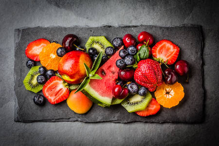Ягоды и фрукты на черной тарелке