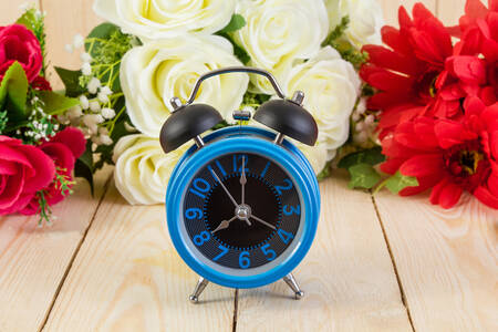 Blue alarm clock and flowers