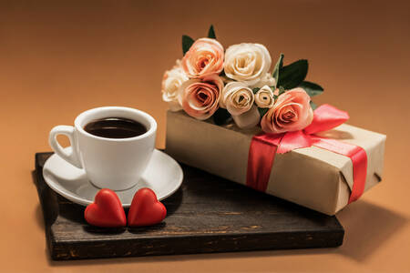 Eine Tasse Kaffee, ein Geschenk und Rosen