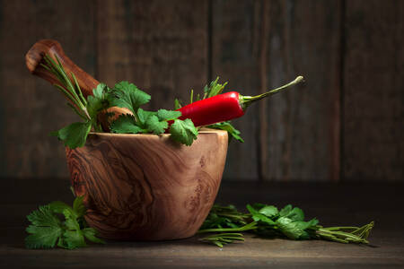 Wooden mortar with herbs and pepper