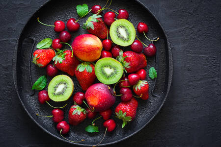 Beeren und Früchte auf einer schwarzen Platte