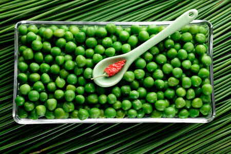 Guisantes verdes en un recipiente de vidrio